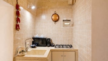A compact kitchen with a gas stove, a coffee maker, and a microwave.