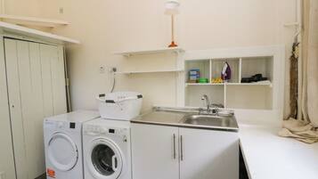 Un área de lavandería compacta con lavadora, secadora, lavabo y estantes de almacenamiento.