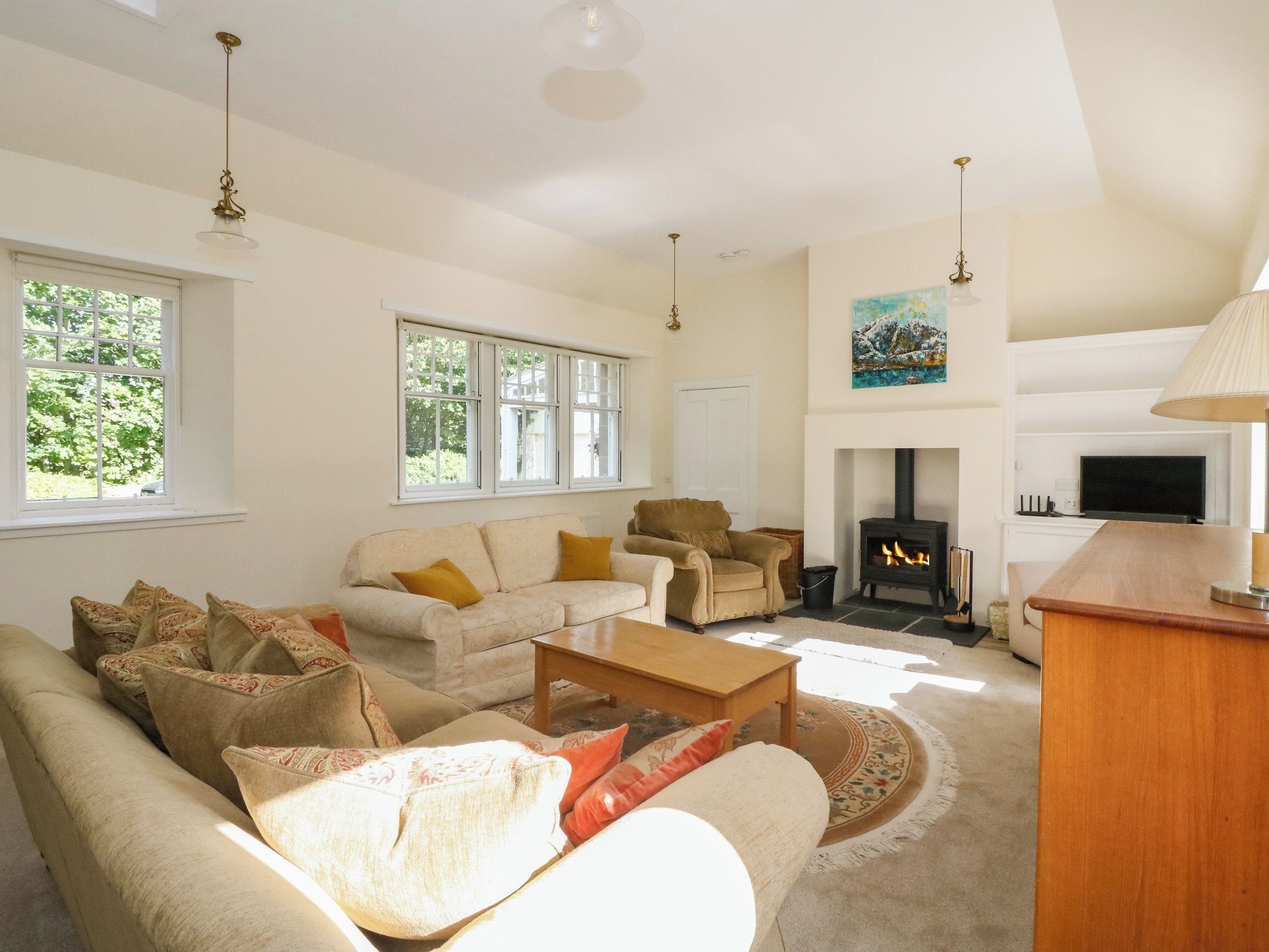 A spacious living room with a sofa set, a fireplace, and a television.
