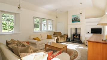 A spacious living room with a sofa set, a fireplace, and a television.