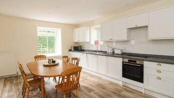 A modern kitchen with white cabinets, a black countertop, and a dining table with wooden chairs.