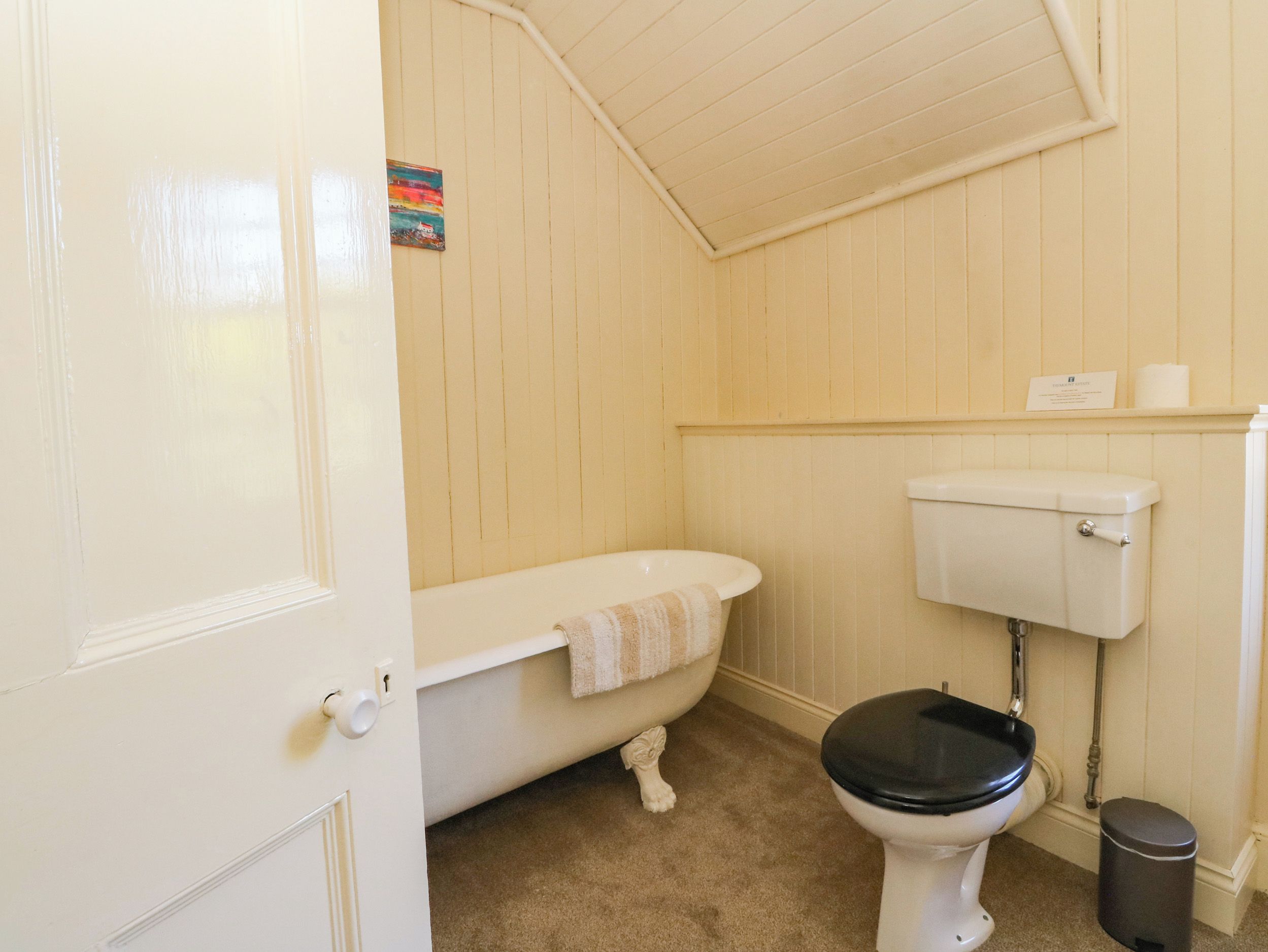 Baño con bañera, inodoro y cubo de basura.
