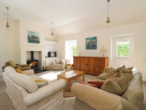 A spacious living room with a fireplace, sofas, a television, and artwork on the walls. - West House (Perth)