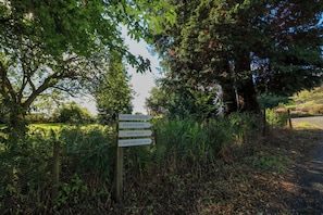 Un panneau indicateur avec des flèches pointant vers « Taymount House », « Estate House », « West House » et « Gardener’s Cottage ».