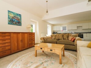 A living room with a wooden cabinet, a sofa, a coffee table, and a painting on the wall.