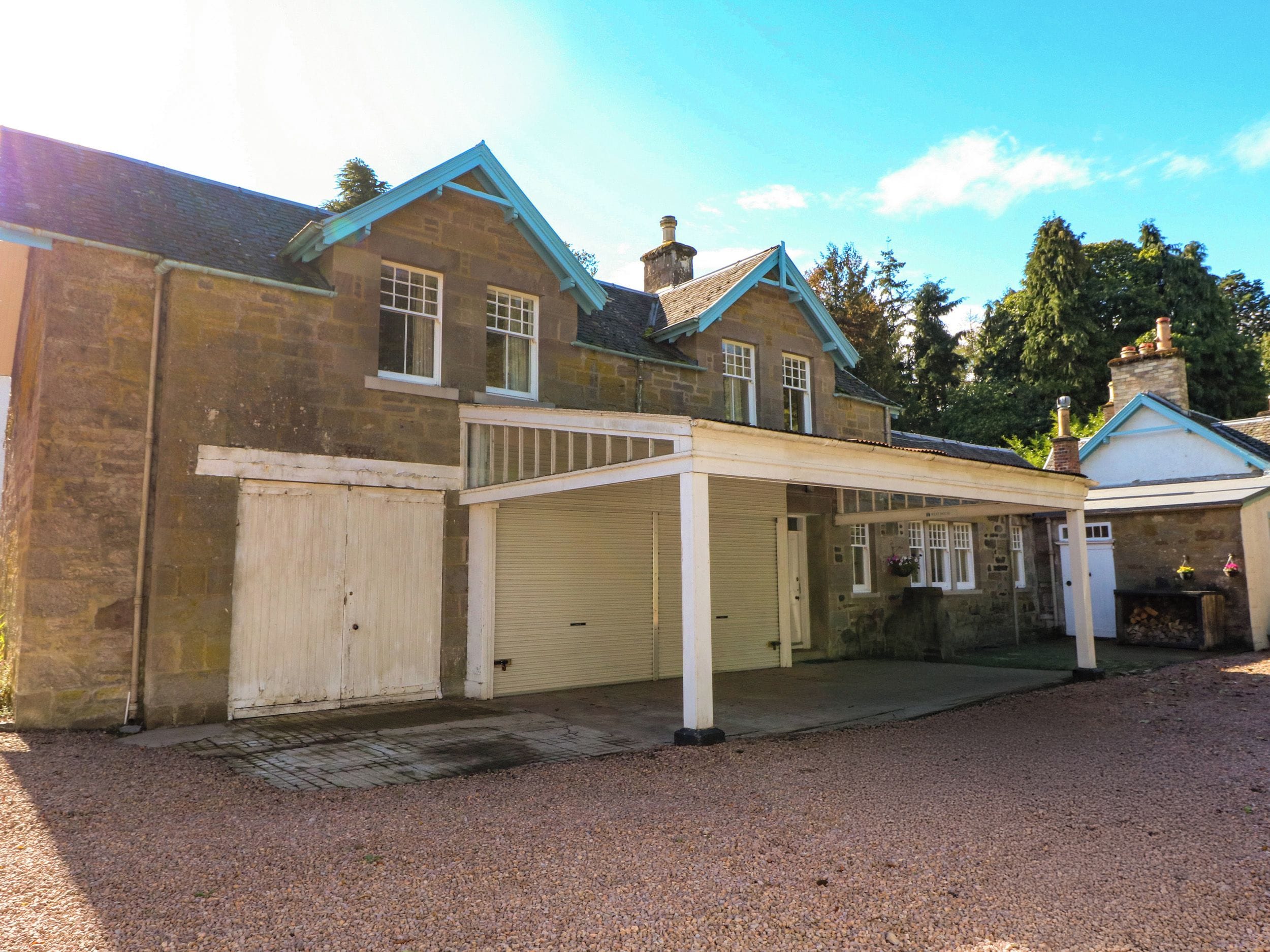 A two-story stone building with a covered driveway and a garage.