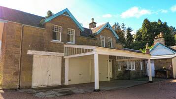 A two-story stone building with a covered driveway and a garage.