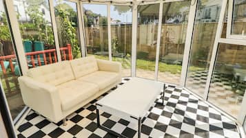A conservatory with a checkered floor, a white sofa, and a small table.