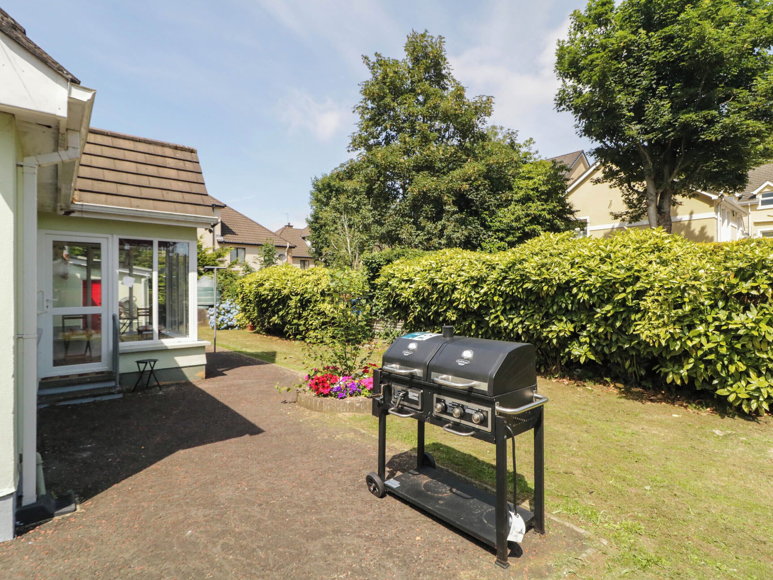 A backyard with a barbecue grill, a small patio table, and a house with a white exterior and brown roof.