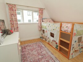 Habitación infantil con literas, un escritorio pequeño y una ventana con cortinas.