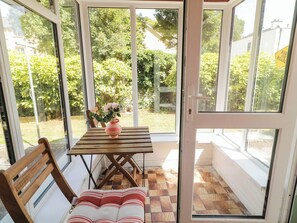 A conservatory with a wooden table, a chair, and a vase with flowers.