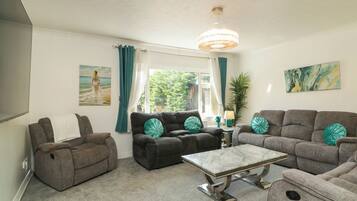 A living room with a sofa set, a coffee table, and a chandelier.