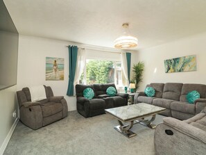Een woonkamer met een zithoek, een salontafel en een kroonluchter.
