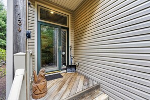 A wooden porch with a metal number plaque, a door with a notice, and a small wooden sculpture. - Luxury Chalet | Hot Tub, Ski Views & Lake Club (Lake Harmony)