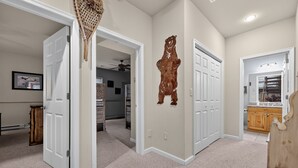 A hallway with carpeted floors, white doors, and a wooden cabinet. - Luxury Chalet | Hot Tub, Ski Views & Lake Club (Lake Harmony)