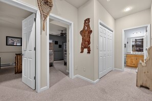 A hallway with carpeted floors, white doors, and a wooden cabinet. - Luxury Chalet | Hot Tub, Ski Views & Lake Club (Lake Harmony)