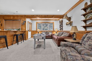 A cozy living room with a wooden interior, a sofa, a coffee table, and a fireplace. - Luxury Chalet | Hot Tub, Ski Views & Lake Club (Lake Harmony)