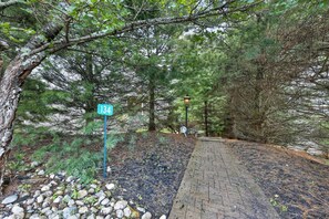 A paved pathway with a signpost indicating the number 134, surrounded by dense trees and a stone border. - Luxury Chalet | Hot Tub, Ski Views & Lake Club (Lake Harmony)