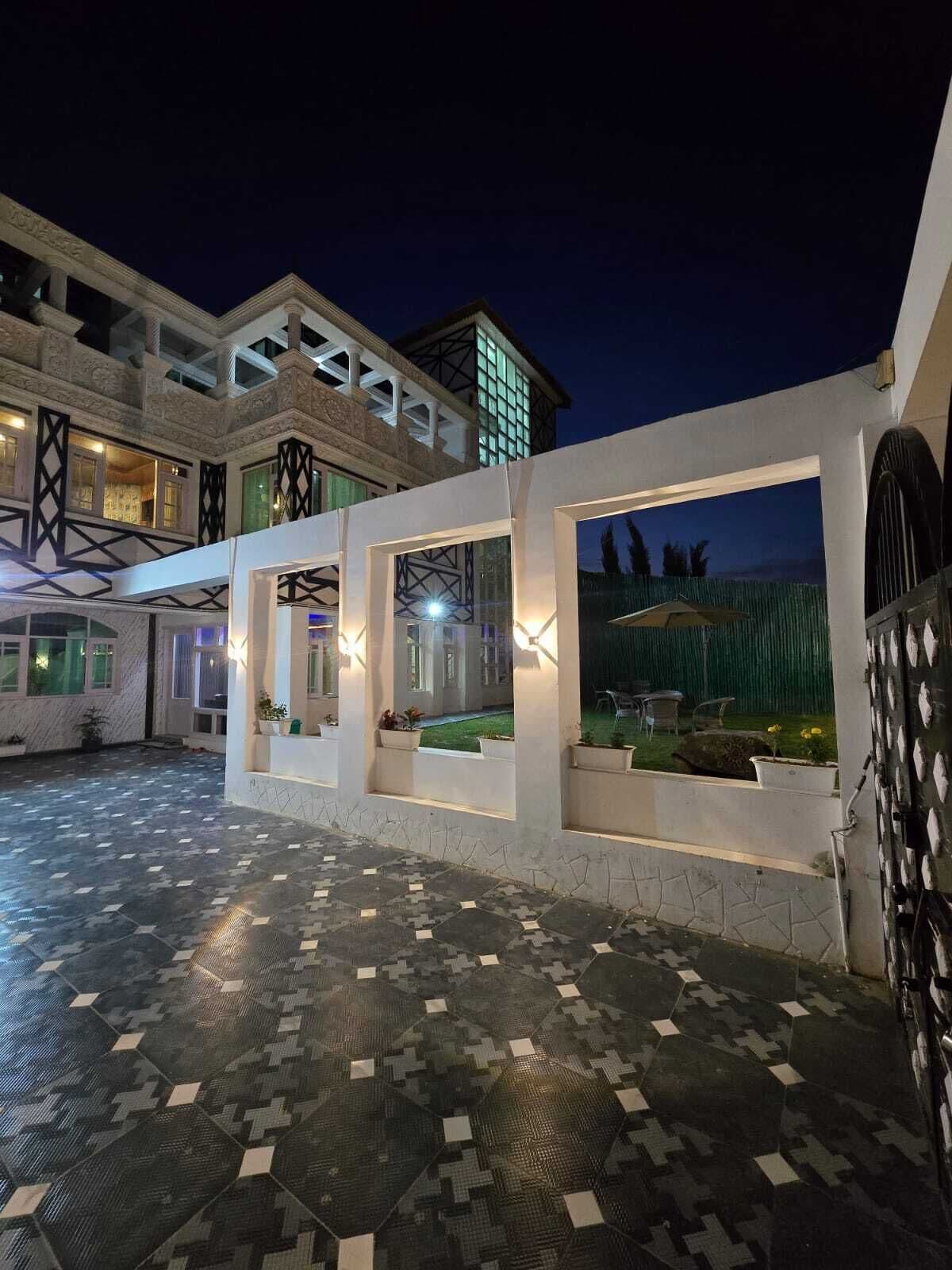 A hotel courtyard with a patterned floor, outdoor seating, and a view of the building's architecture.
