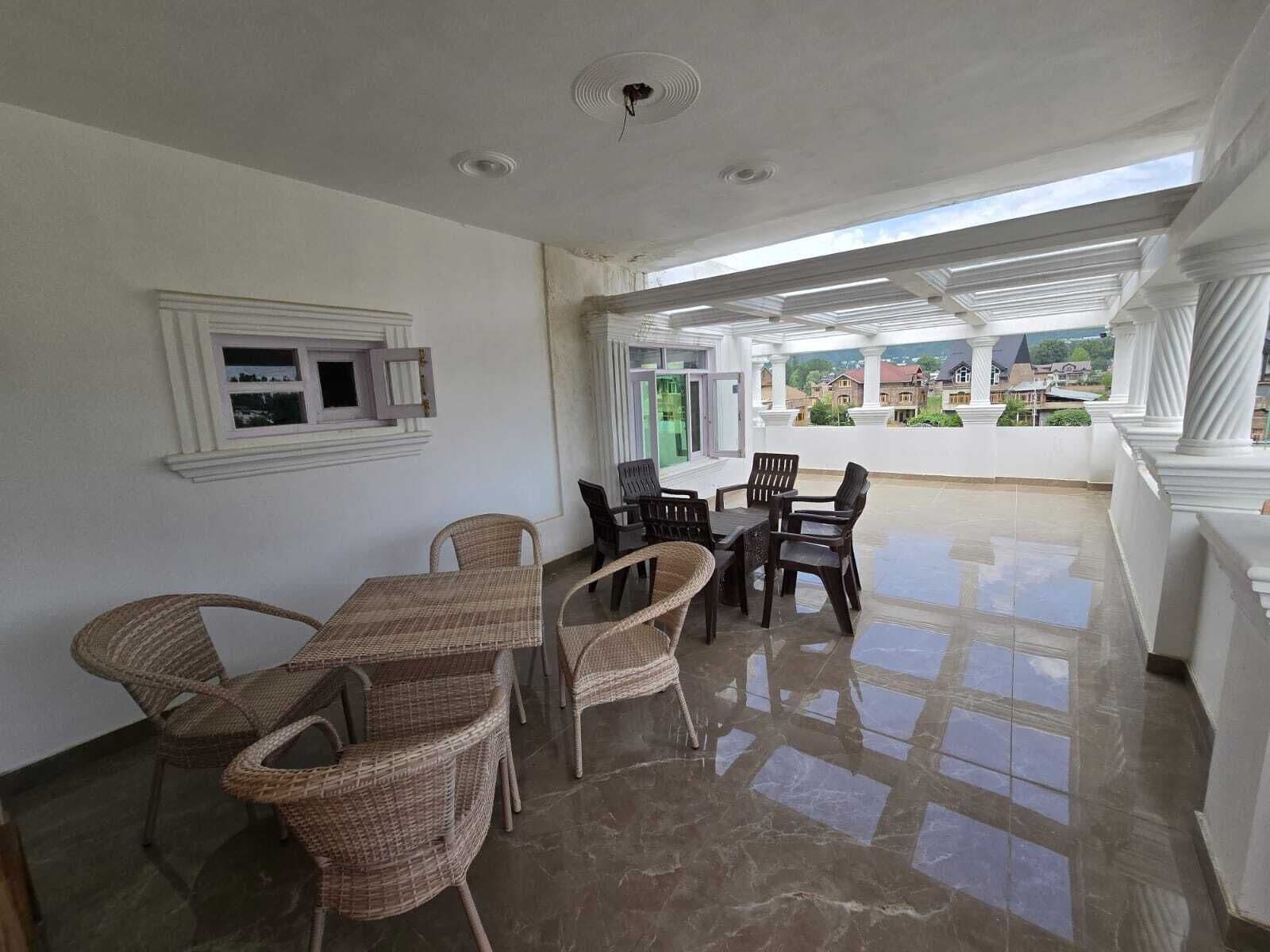 A spacious patio with a dining area featuring wicker furniture and a tiled floor.