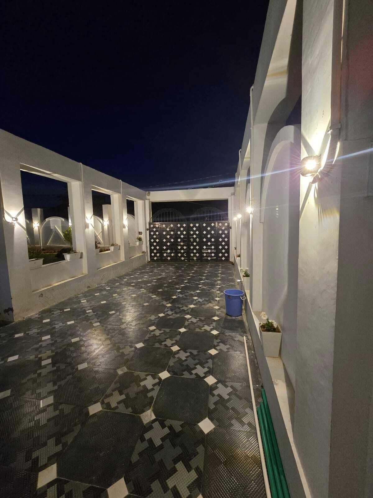 A rooftop terrace with a patterned floor, a gate, and wall-mounted lights.
