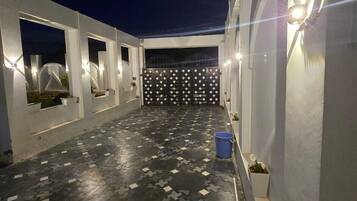 A rooftop terrace with a patterned floor, a gate, and wall-mounted lights.