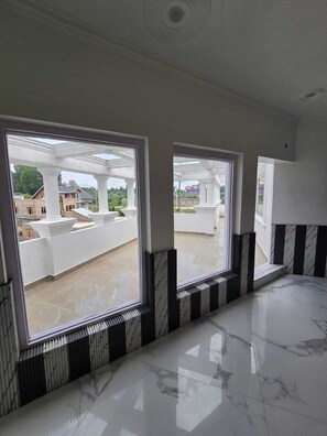 Una habitación con ventanas amplias, piso de mármol y vista a un edificio con columnas.