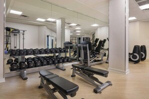 Ein Fitnessstudio mit Krafttrainingsgeräten, Bänken und Kurzhanteln.