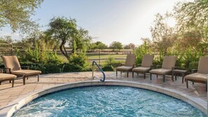 Una piscina con sillones de descanso y una valla metálica.