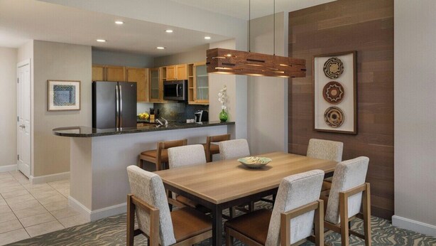 Una cocina moderna con una isla central, sillas de madera y una mesa de comedor.