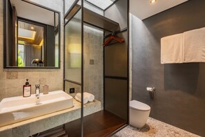 Ein modernes Badezimmer mit einer gläsernen Duschkabine, einem Waschbecken mit Toilettenartikeln und einer Toilette.