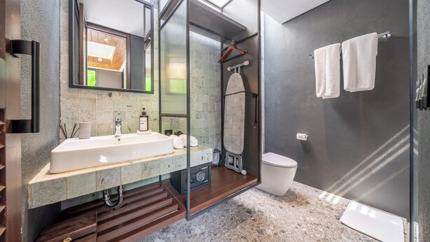 Uma casa de banho moderna com chuveiro envidraçado, toucador com lavatório e espelho.