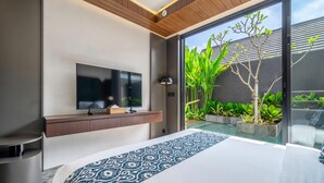 Quarto moderno com uma cama grande, televisão de tela plana na parede e uma porta de vidro deslizante para um jardim.