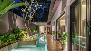 Uma área de piscina moderna ao ar livre com um deck de madeira, cercada por jardineiras com diversas plantas.