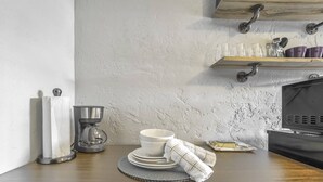 A kitchen with a coffee maker, a plate stack, and a towel on a table.