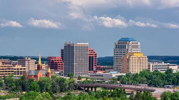 A cityscape with modern buildings, a prominent church steeple, and a bridge.