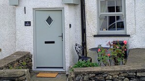 A house with a grey door, a small window, and a stone wall. - Bobbin Nook (Kendal)