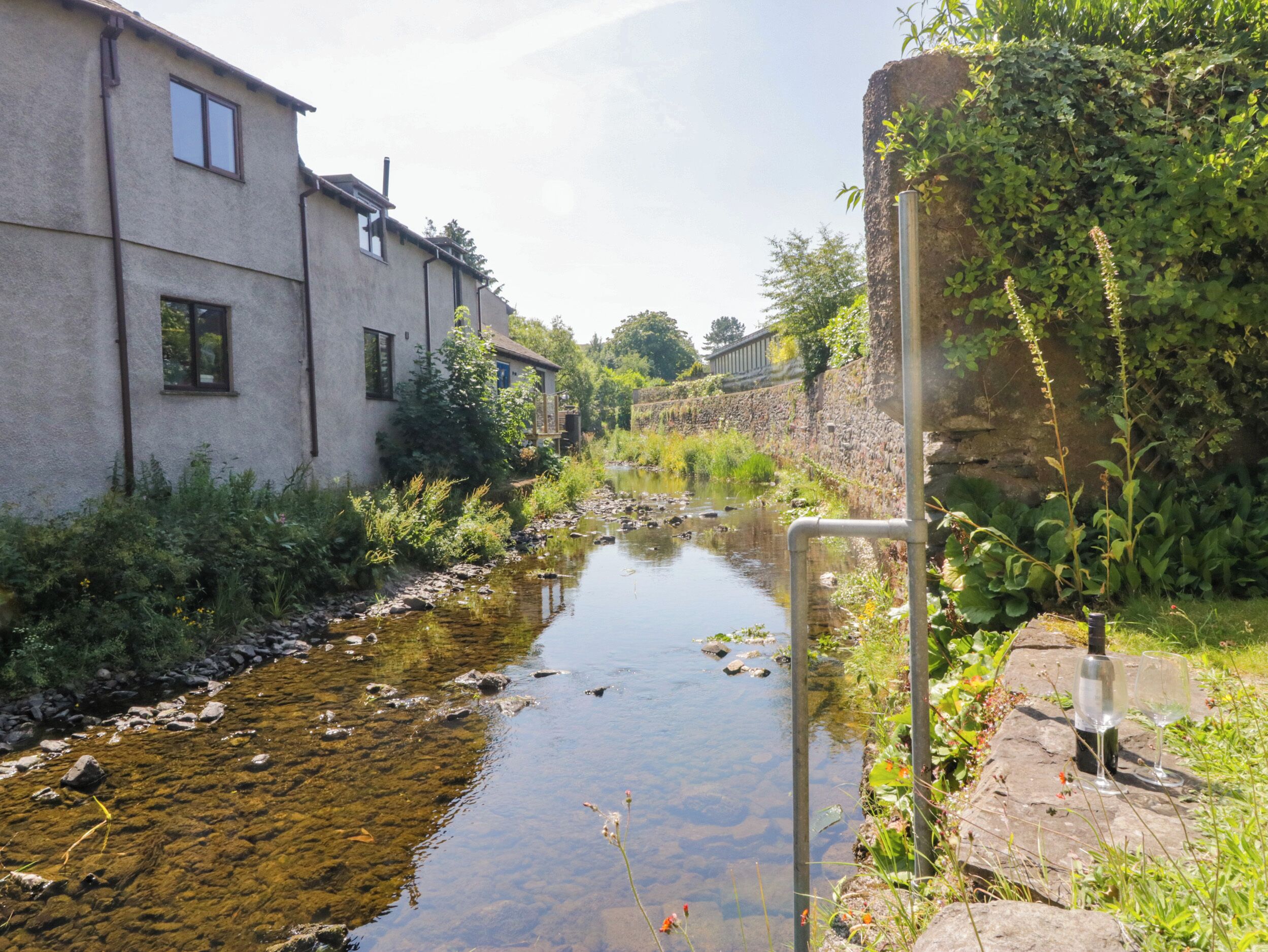 A narrow waterway with a building on one side and a stone wall on the other.