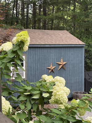 Un petit abri de jardin avec un toit en pente, deux étoiles décoratives et une fenêtre.