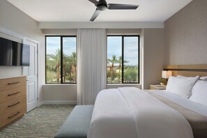 A hotel room with a bed, a TV, a ceiling fan, a nightstand, and a window with a view of palm trees. - 2 Bedroom Villa at Scottsdale Resort Kid-Friendly (Scottsdale)