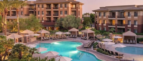 Un hotel con varias edificaciones, piscina y zonas de estar al aire libre.