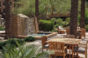 An outdoor patio area with a stone waterfall feature, wooden seating, and lush greenery. - 2 Bedroom Villa at Scottsdale Resort Kid-Friendly (Scottsdale)