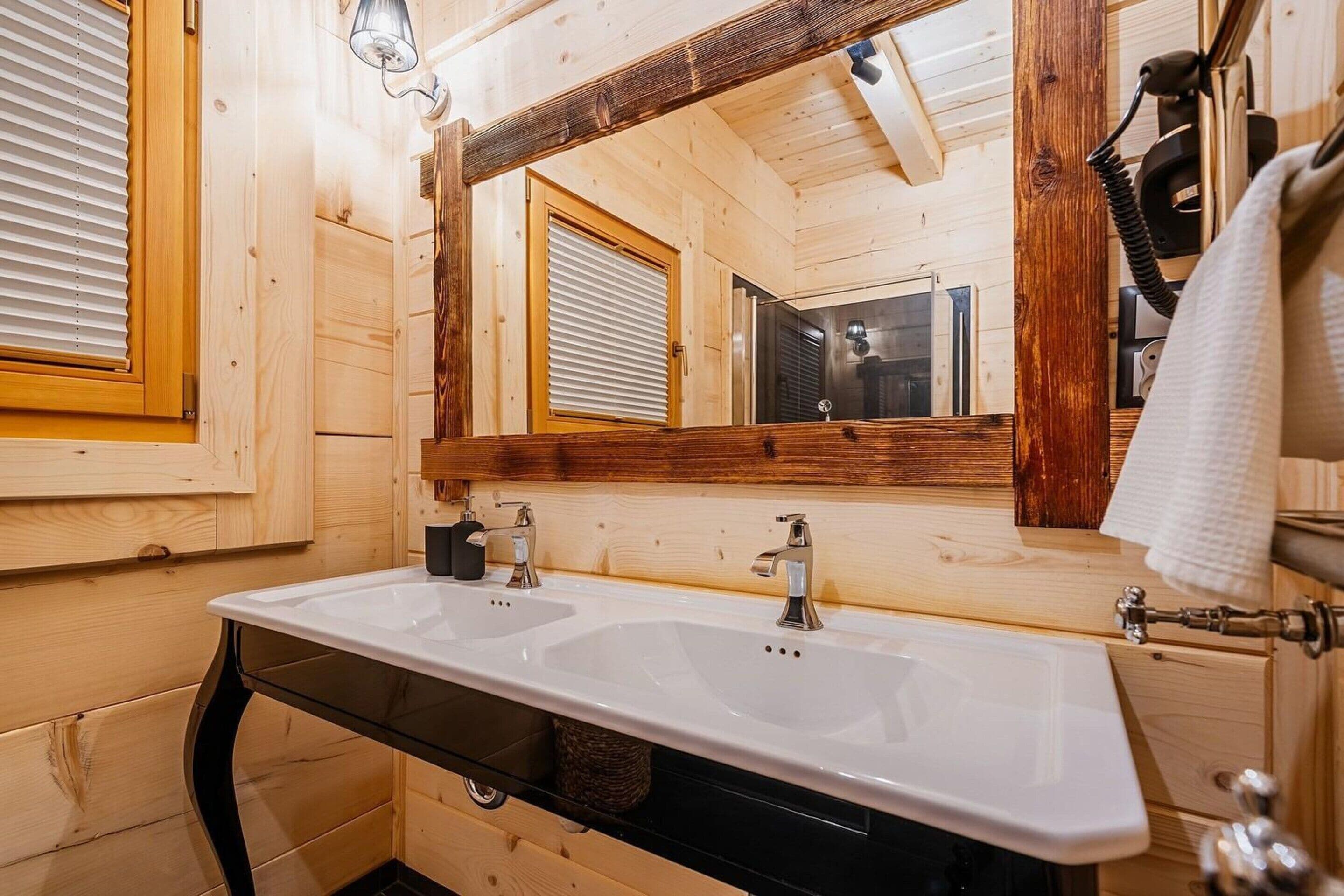 Ein Holzinterieur mit einem Waschbecken, einem Spiegel und einem Handtuchhalter.