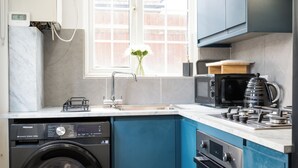 Une cuisine moderne équipée d’un lave-linge, d’un évier, d’une fenêtre avec vue et d’une cuisinière.