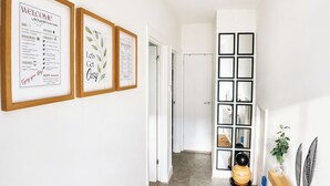 Un couloir orné de panneaux d’accueil encadrés, une porte et une plante décorative.