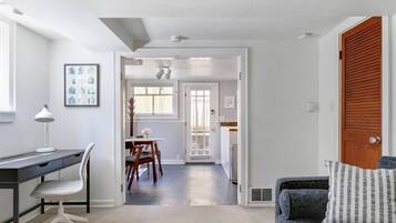 A modern interior with a desk, chair, dining table, and a sofa.