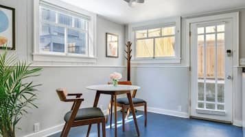 A room with a round table and two chairs, a potted plant, and a door leading outside.