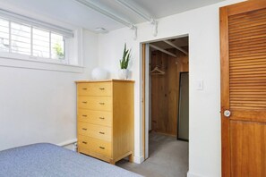 Un dormitorio con un aparador de madera, una cama, un ventanal y una puerta que da a un armario.