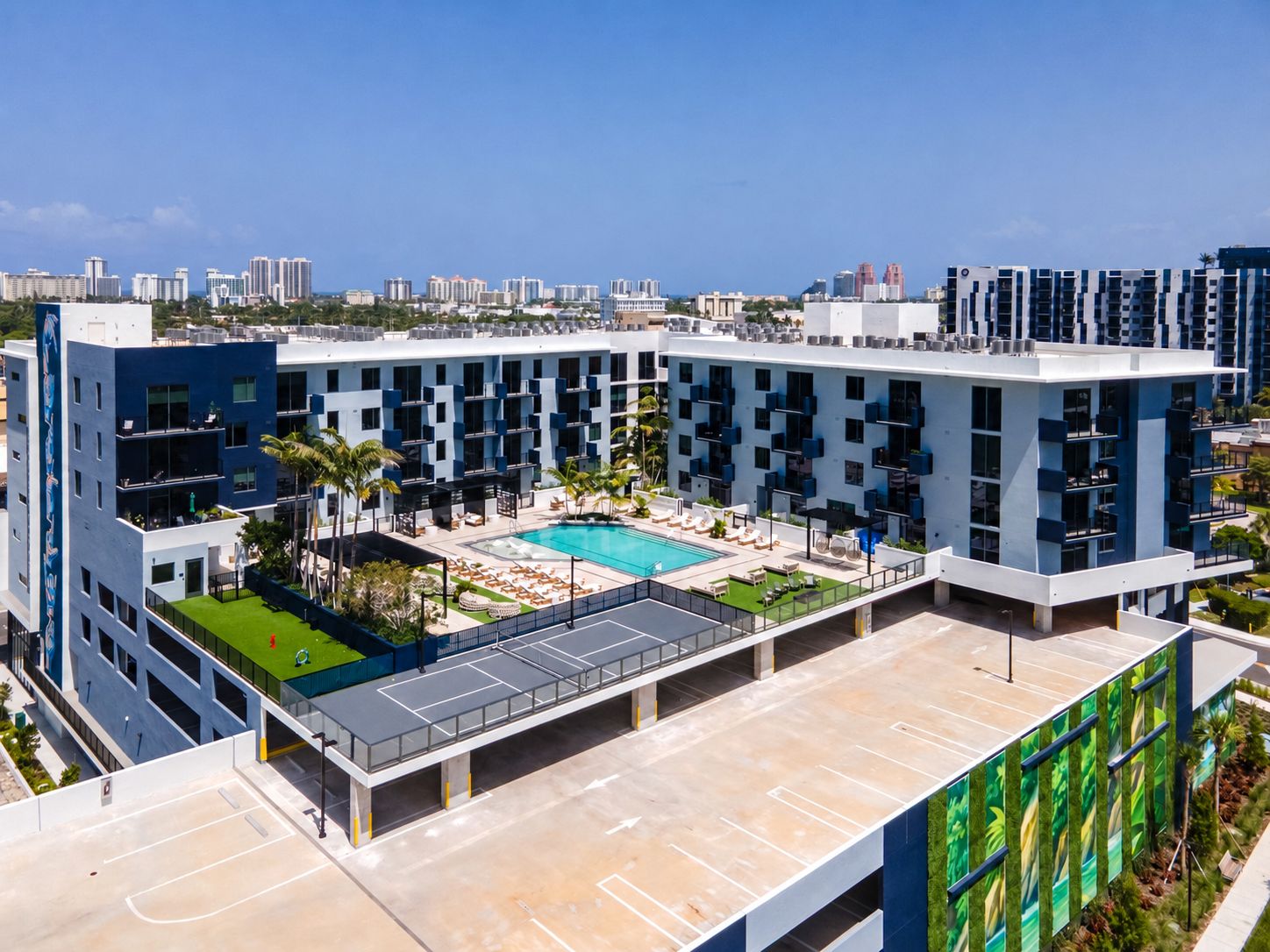 A modern hotel with a rooftop pool, multiple floors, and a view of the city skyline.