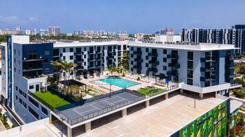 A modern hotel with a rooftop pool, multiple floors, and a view of the city skyline.
